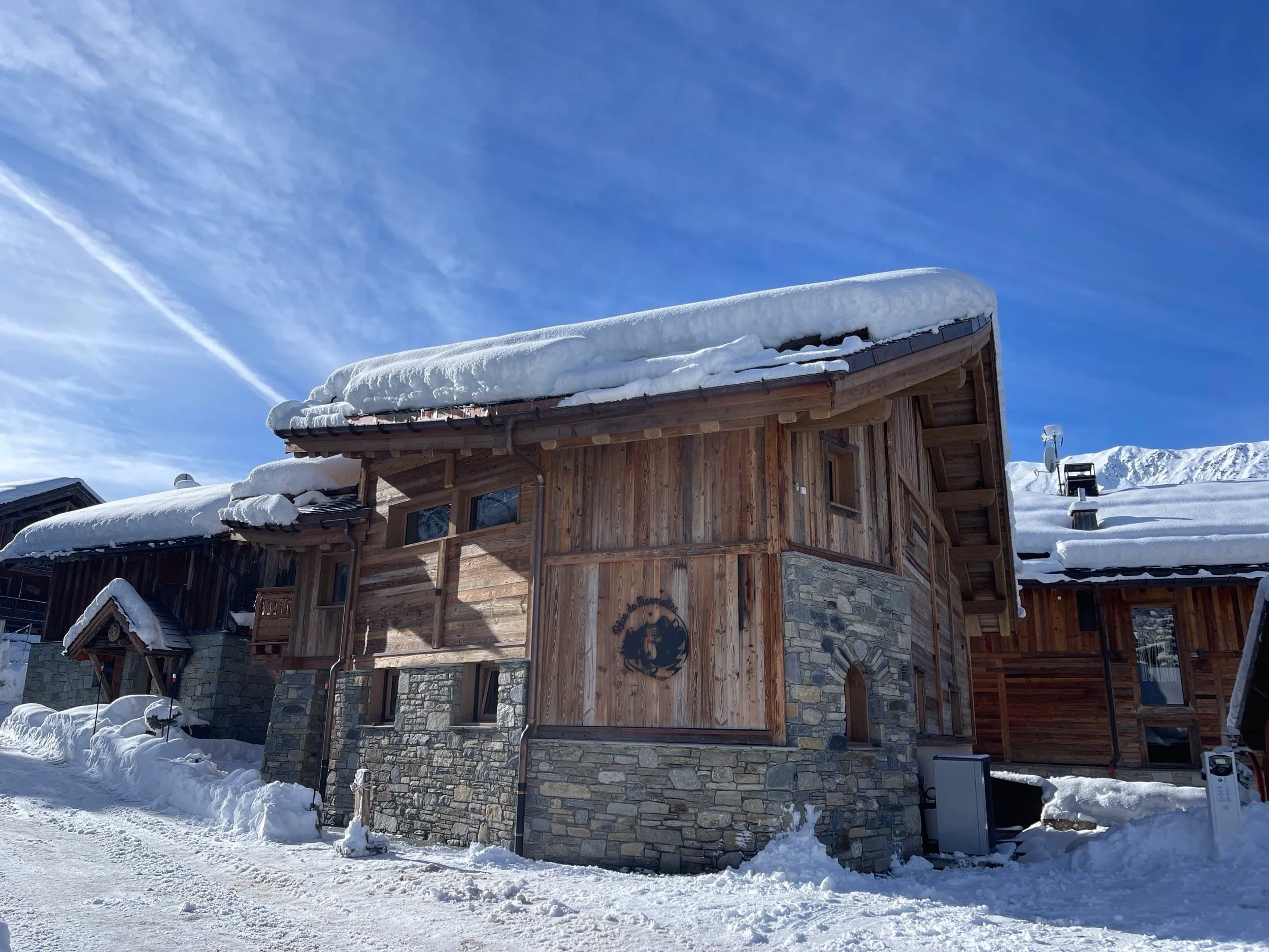 Side of the chalet with the marmot emblem, its roof heavy with snow