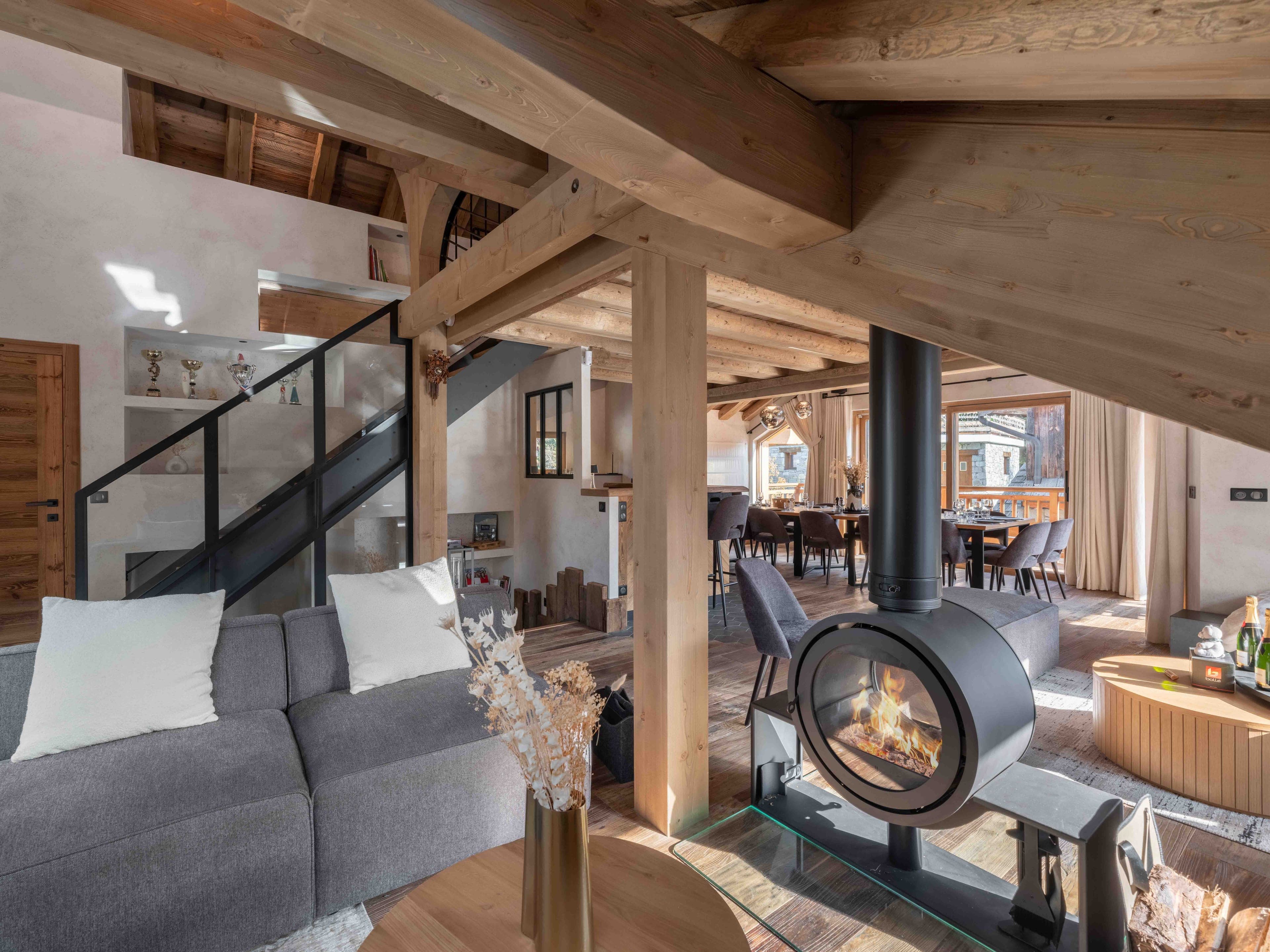 Living room with a round suspended fireplace, grey sofa and open staircase